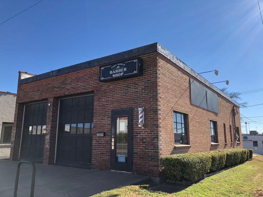 Barber shop building with brick exterior and large windows on a clear sunny day.