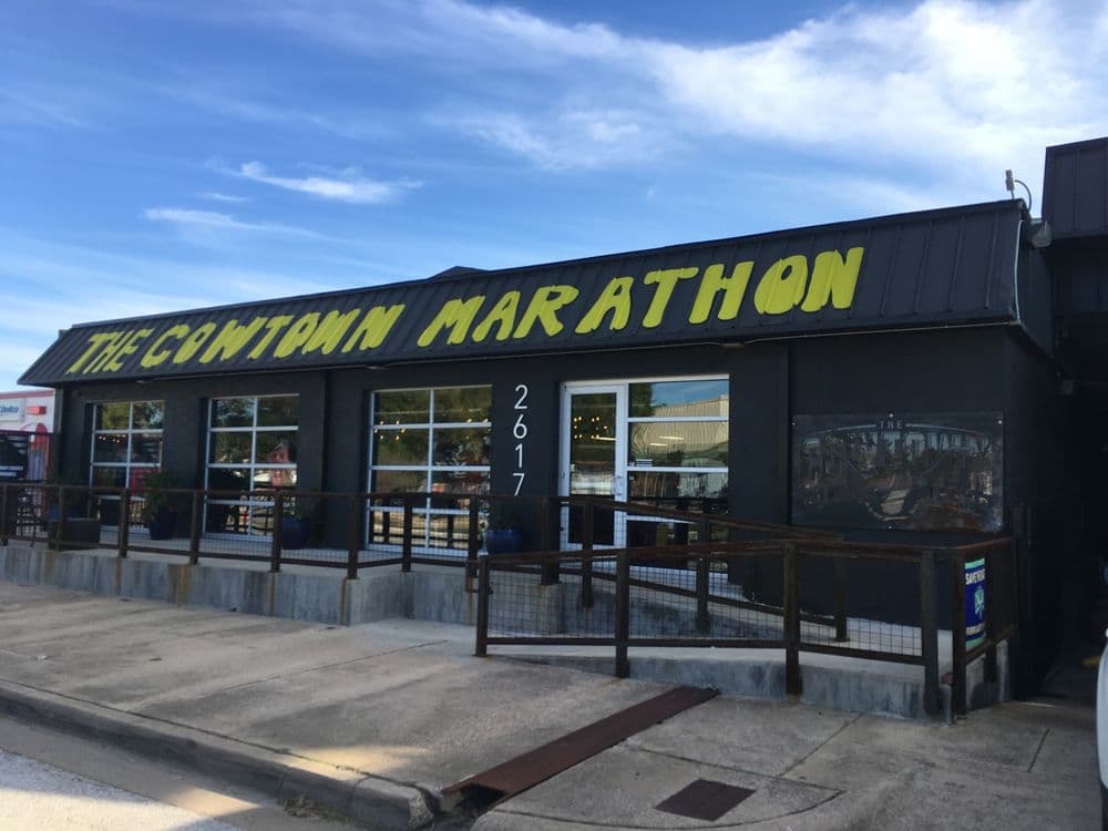 The Cowtown Marathon storefront with yellow signage and large windows on a clear day.