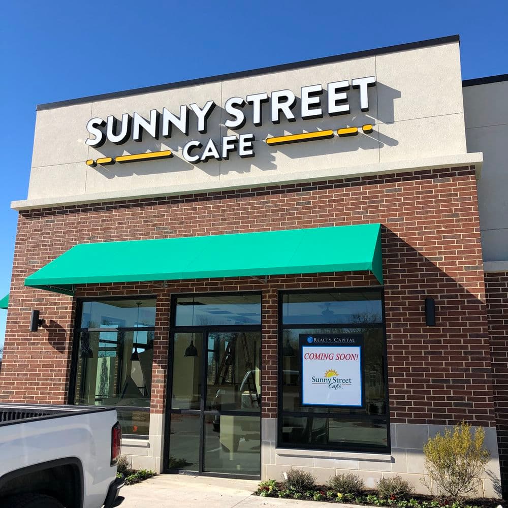 Sunny Street Cafe building exterior with green awning and "Coming Soon" sign.