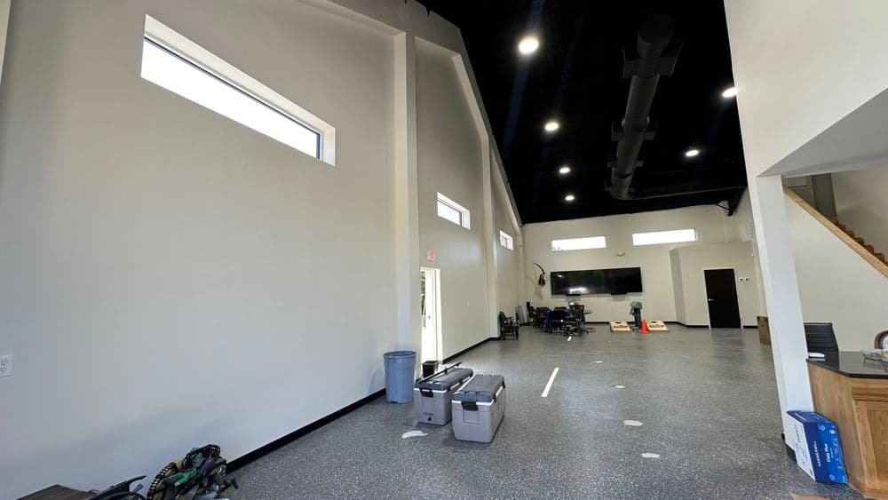 Spacious modern interior of a facility with high ceilings, large windows, and workstations.