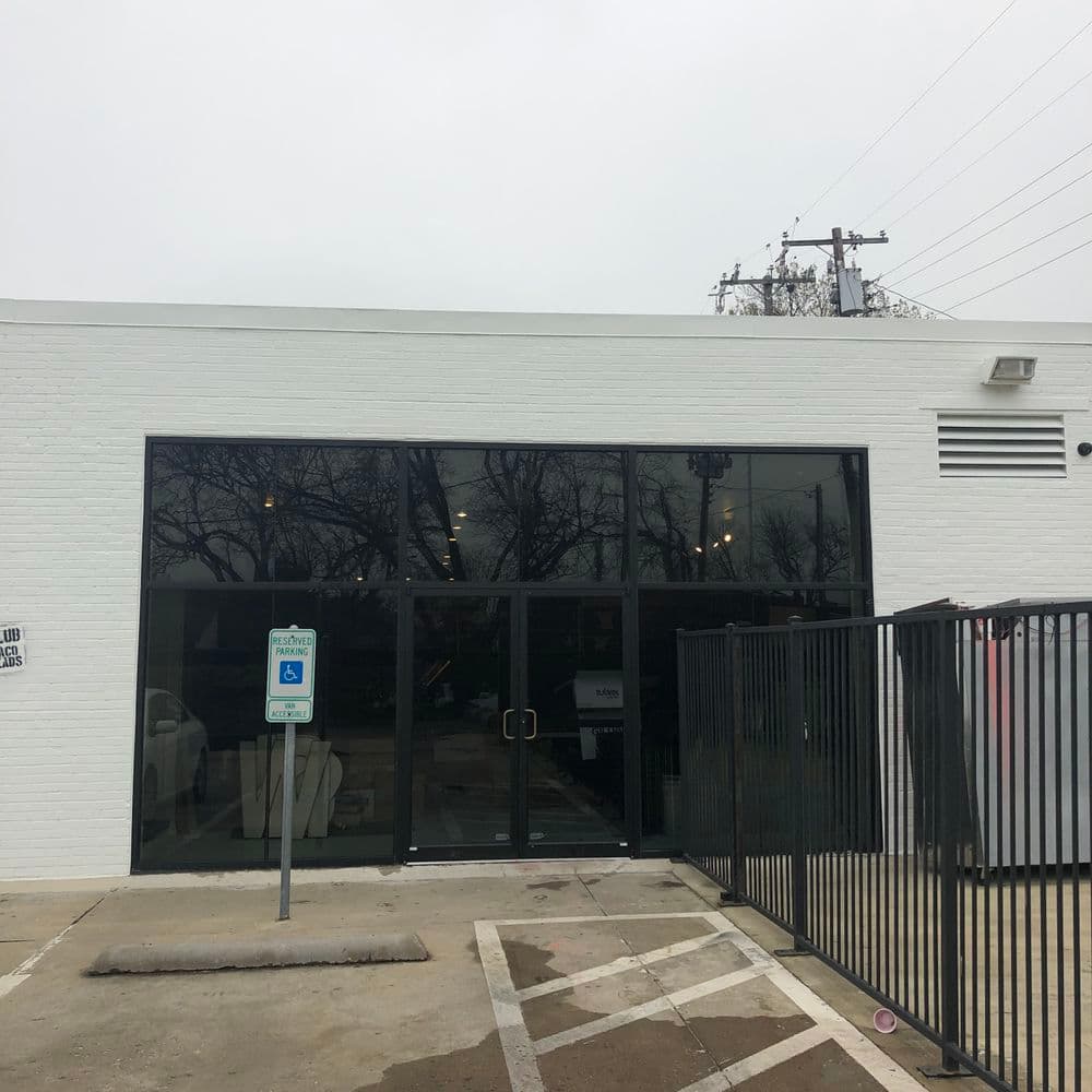 Modern white building exterior with large glass windows and accessible parking area.