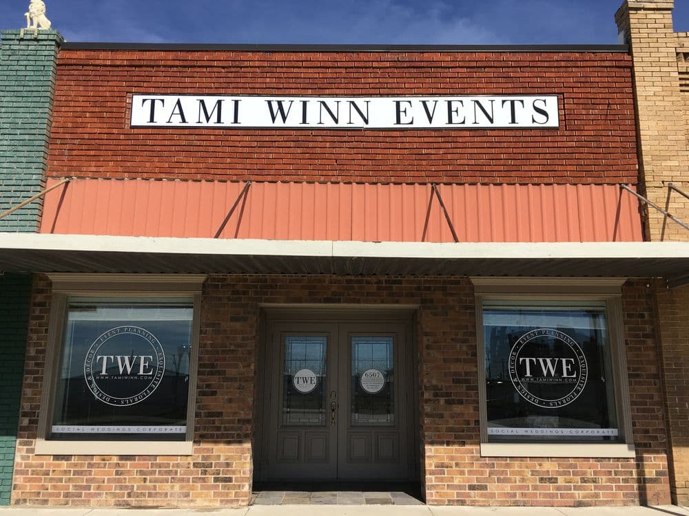 Tami Winn Events storefront featuring large windows and brick facade in a vibrant downtown setting.