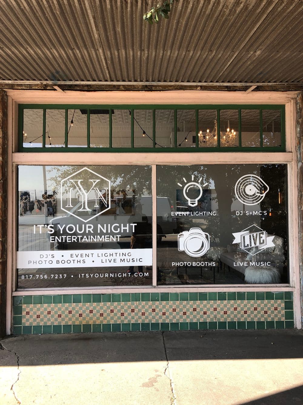 Window display for It's Your Night Entertainment showcasing event lighting, DJs, photo booths, and live music.
