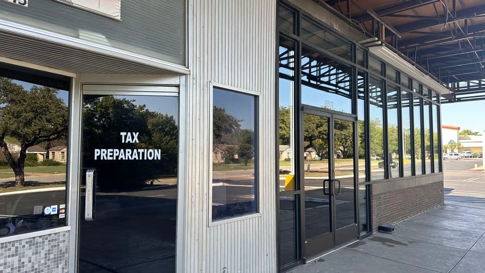 Tax preparation office exterior with large glass windows and trees in the background.