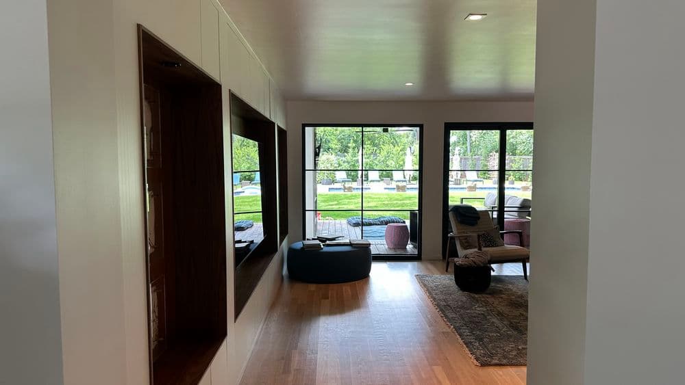 Modern interior with open living space, large windows, and outdoor view of a grassy area.