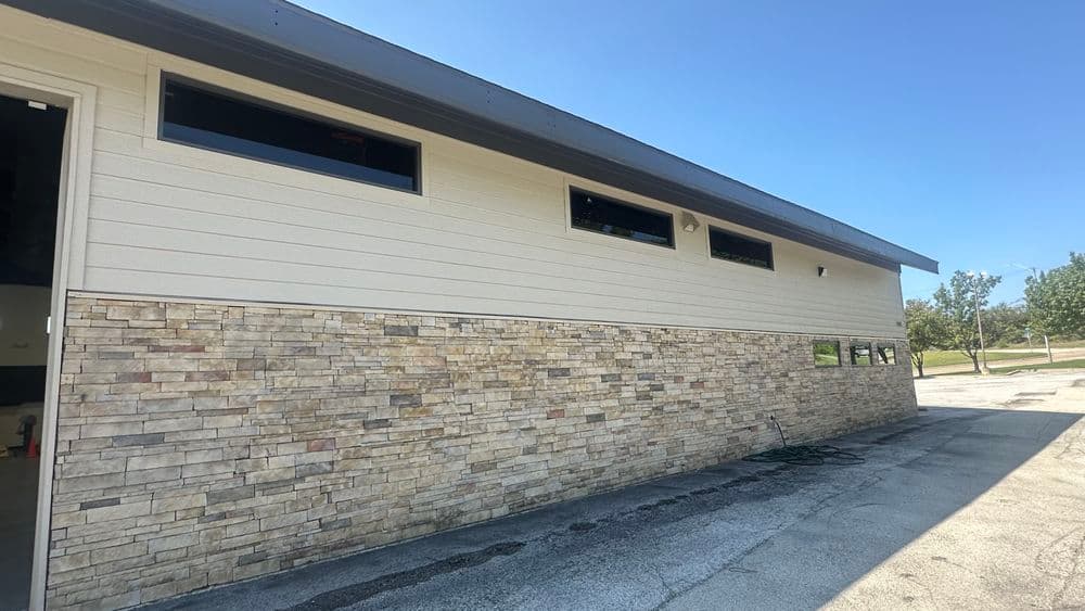 Modern building exterior with stone accents and large windows on a sunny day.
