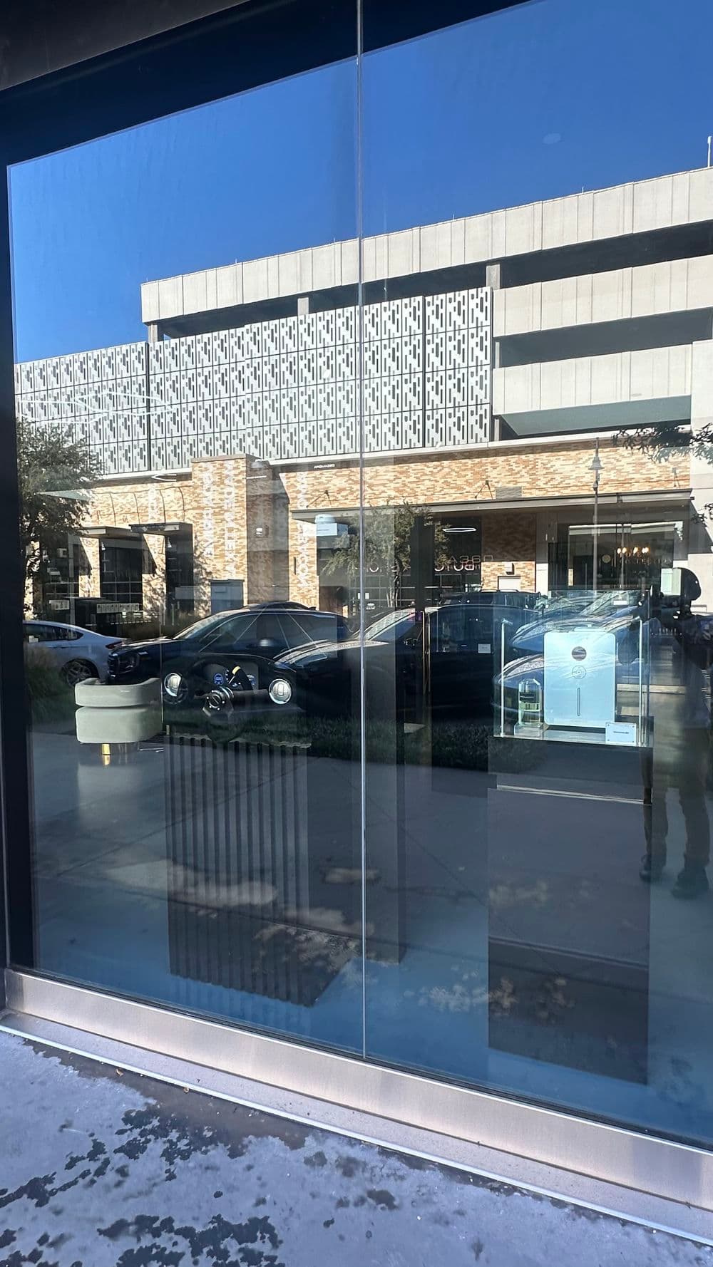 Luxury store window showcasing modern architecture and reflections of nearby buildings.