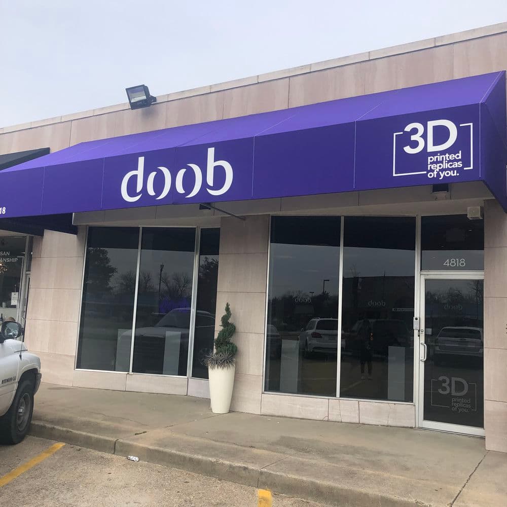3D printing store exterior with sign "doob" and tagline "printed replicas of you" in purple.