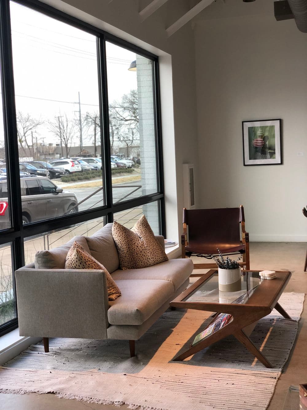 Modern living room with gray sofa, decorative pillows, wood coffee table, and large windows.