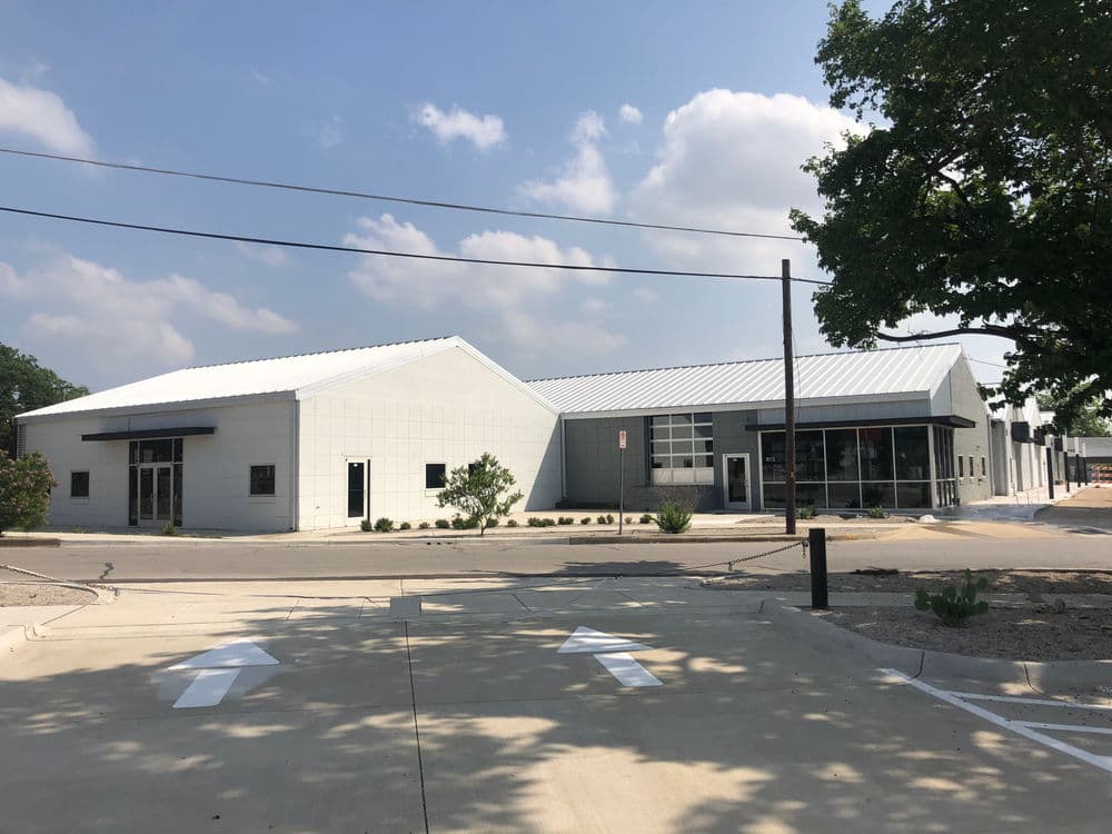 Modern commercial building with a sleek design and spacious entrance, surrounded by greenery.